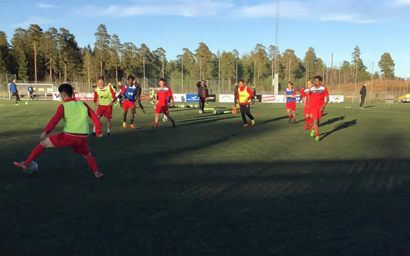 Grupo de jugadores entrenando con petos en un rondo sobre césped